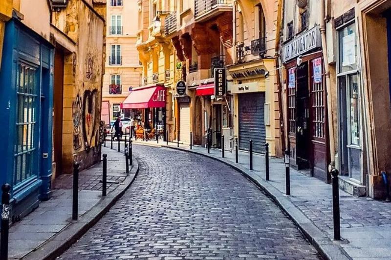 Un bus parisien passant devant une librairie pittoresque du Quartier Latin, avec des étudiants et des touristes explorant la zone près de Notre-Dame de Paris.